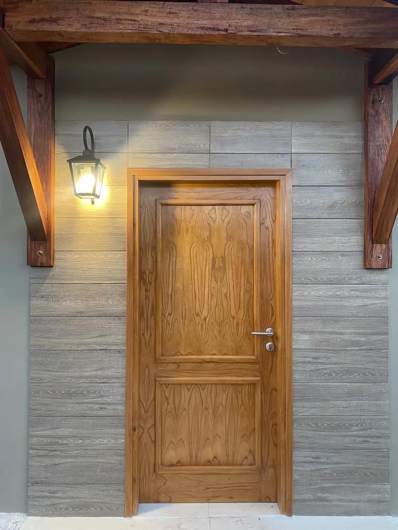 Puerta de madera enmarcada en revestimiento simil piedra, San Lorenzo - OGA Constructora