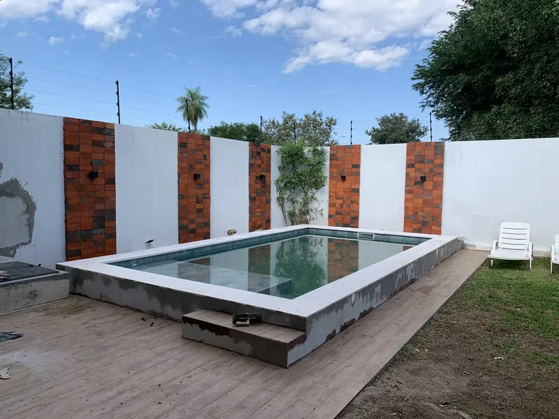 Piscina con muro decorativo de ladrillo y deck de madera, remodelacion en Loma Pyta - OGA Constructora