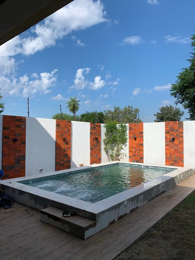 Vista en angulo de la piscina y el muro decorativo, Loma Pyta - OGA Constructora
