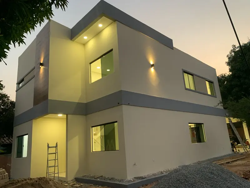 Fachada moderna de dos plantas iluminada al atardecer, vivienda Ruben Aranda Luque - OGA Constructora