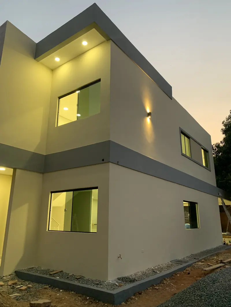 Ventanales iluminados de la vivienda Ruben Aranda al anochecer, Luque - OGA Constructora