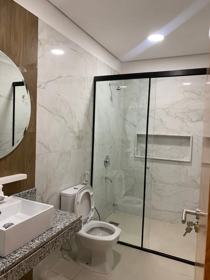 Bano con box de vidrio y revestimiento de marmol, vivienda Ruben Aranda Luque - OGA Constructora